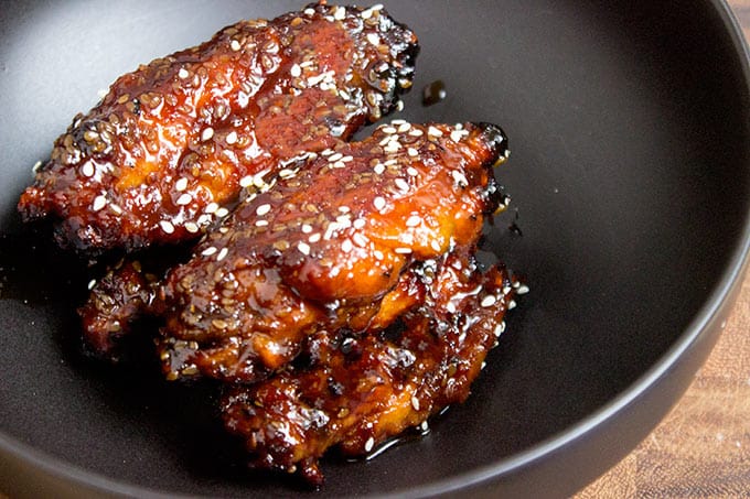 Sticky Asian chicken wings topped with sesame seeds in skillet