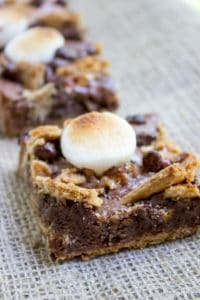 S'mores Brownies start with a graham cracker base and rich chocolate brownie. They're topped with buttery graham crackers, milk chocolate chips and toasted marshmallows for the perfect summery treat with no bonfire!