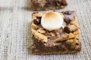S'mores Brownies start with a graham cracker base and rich chocolate brownie. They're topped with buttery graham crackers, milk chocolate chips and toasted marshmallows for the perfect summery treat with no bonfire!