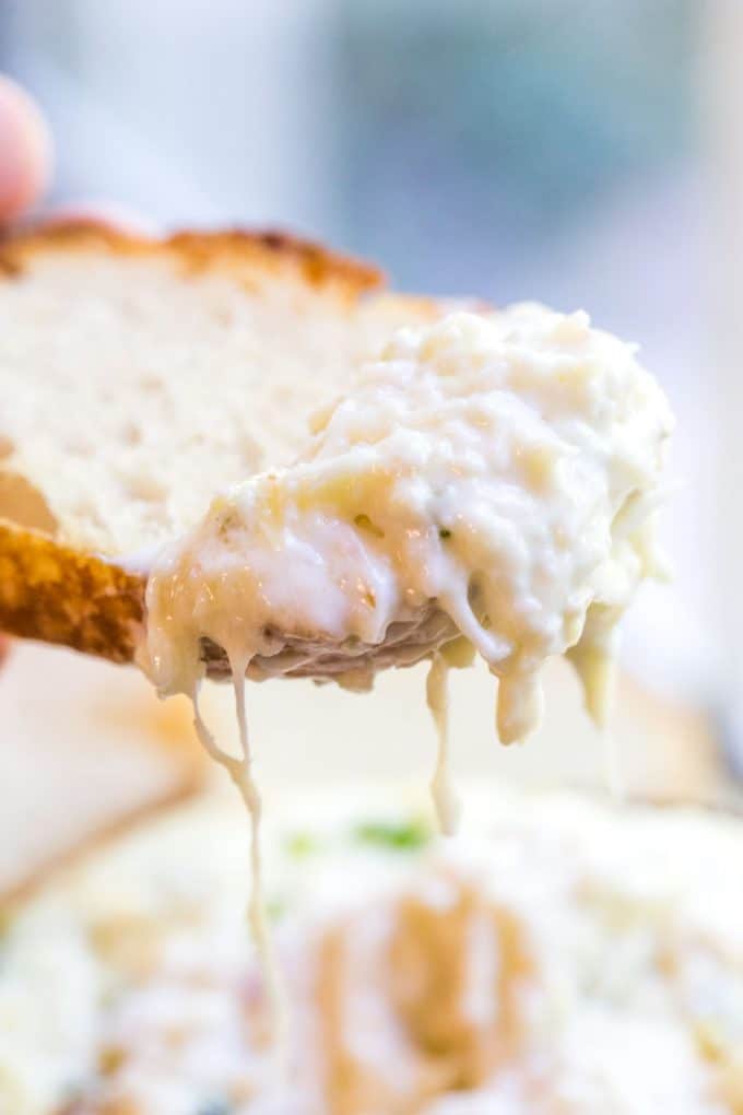 Creamy artichoke dip on crusty piece of bread