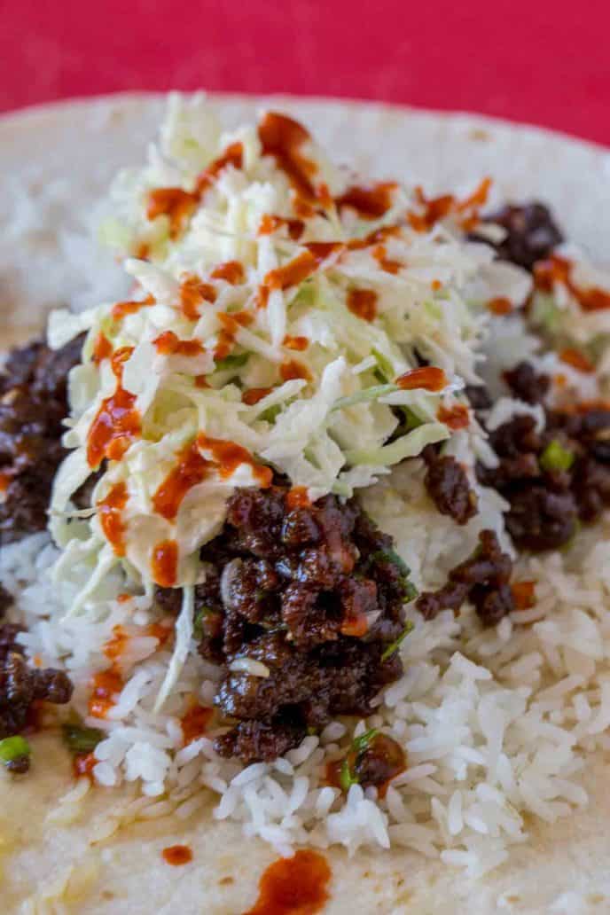 Slaw, Sriracha, Ground Mongolian Beef and Rice in a burrito.