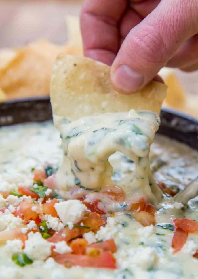 Chip with cheesy melted spinach queso