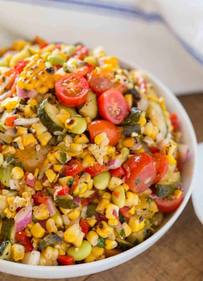 Corn Succotash is the perfect summer side dish made with freshly grilled corn, zucchini, grape tomatoes, red bell peppers, lima beans and red onion. | #summer #sides #sidedish #picnic #dinnerthendessert #easysidedish #vegetarian #corn