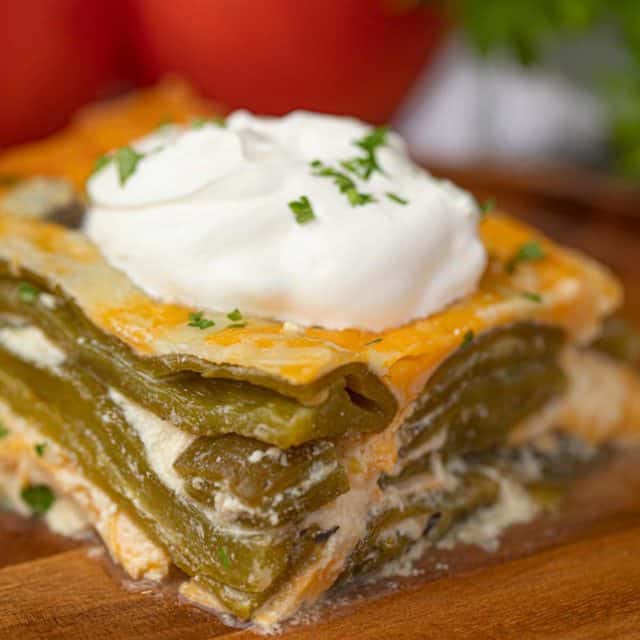 Slice of Chile Relleno Casserole with Green Chiles, Cheddar Cheese and Sour Cream on Wooden Plate
