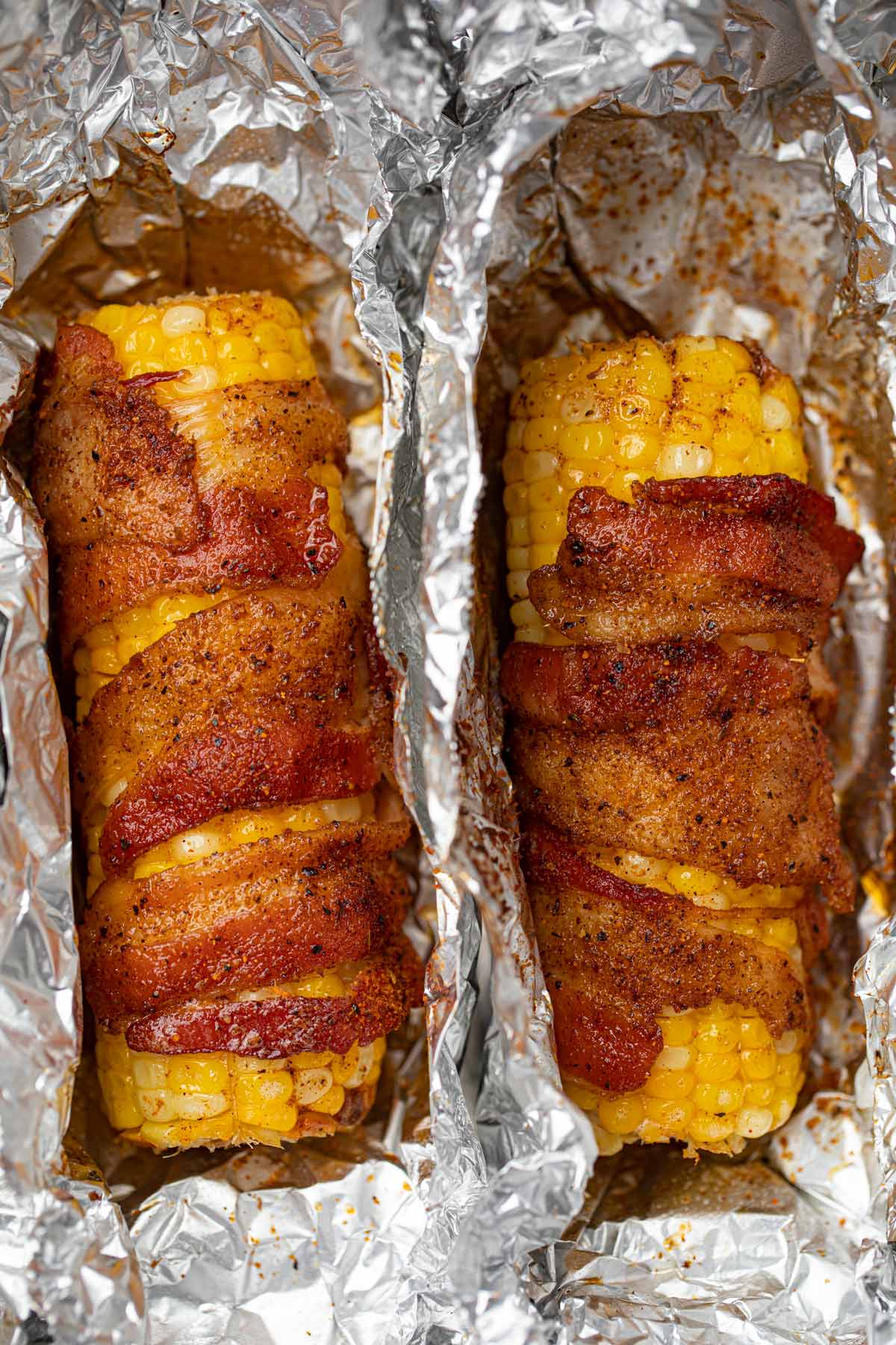 Two bacon wrapped corn on the cobs