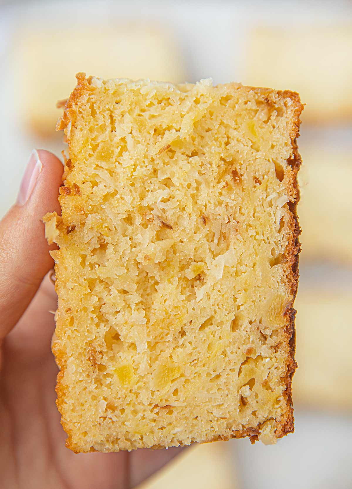 Hand holding slice of Pineapple Coconut Bread