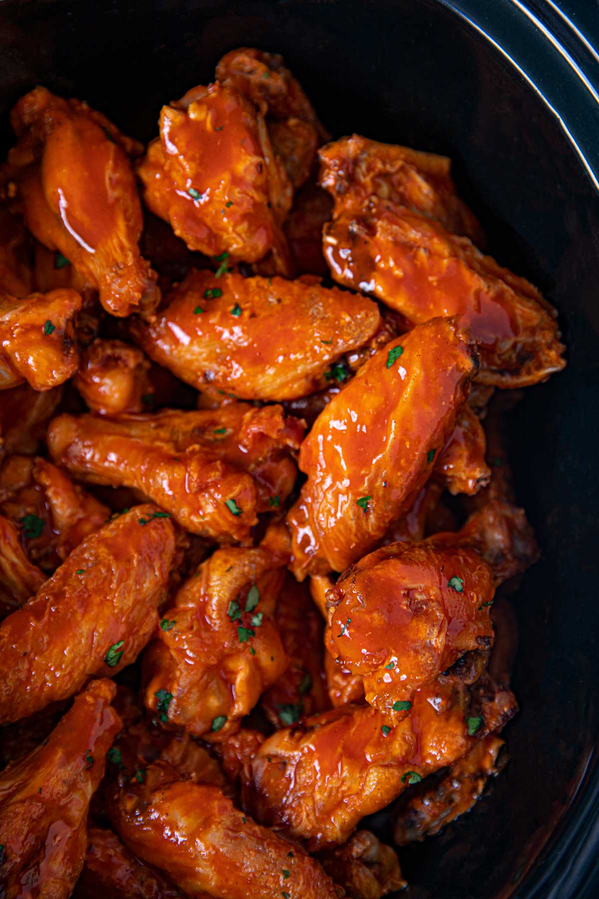 Close up of Slow Cooker Buffalo Wings in black crockpot